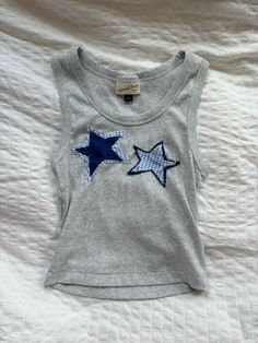 a gray shirt with blue stars on the front and back, sitting on a bed