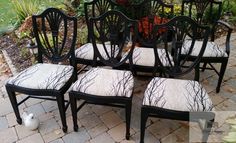 six black dining chairs with white upholstered back and seat cushions on brick patio