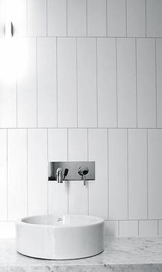 a white sink sitting on top of a marble counter next to a wall mounted faucet