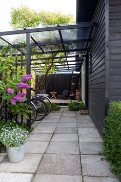 a bike is parked in front of a house with flowers on the ground and plants around it