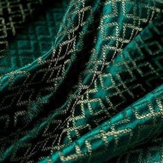 green and gold patterned fabric with white lines on the top, in an up close shot