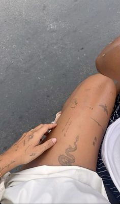 a woman with tattoos on her legs sitting next to a man holding a cell phone