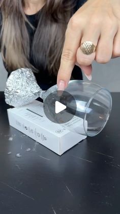 a woman pointing at something in a clear container on top of a black countertop