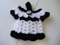 a crocheted black and white dress hanging from a hook on a wall or floor