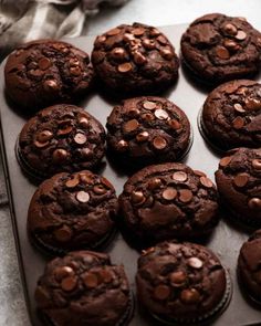 chocolate muffins with chocolate chips on top sitting on a baking sheet, ready to be eaten