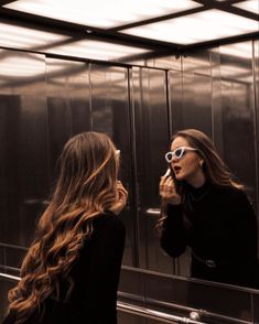 a woman is standing in front of a mirror brushing her teeth and looking at herself in the mirror