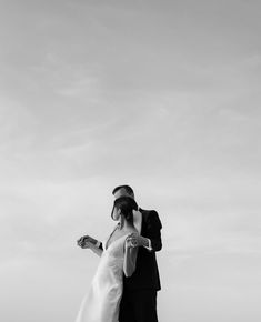 a man and woman standing next to each other on top of a beach near the ocean