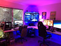 a room with multiple computer screens and monitors on the wall, all lit up by purple lighting