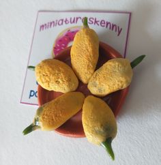 five miniature food items are placed in a small bowl on a white tableclothed surface