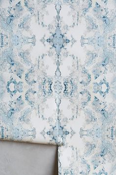 a blue and white wallpaper with an ornate design on it's side, next to a gray chair