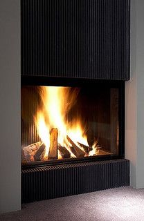 a fire burning in a fireplace next to a wall with red tape on the floor