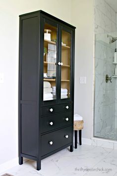 a black cabinet with glass doors in a bathroom