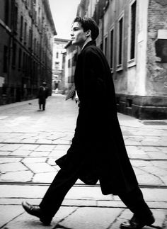 black and white photograph of man walking down the street