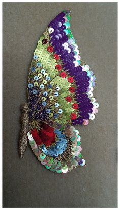 a colorful butterfly with sequins on it's wings sitting on the ground