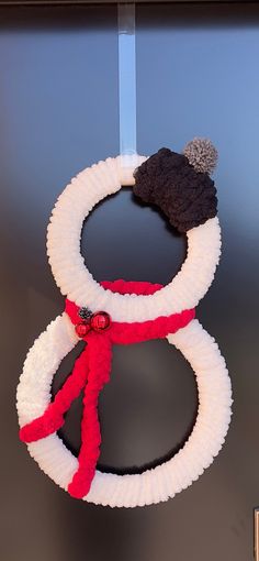 two wreaths with hats hanging on a door hanger in front of a blue wall