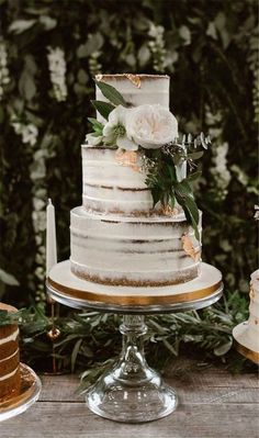 a wedding cake sitting on top of a wooden table next to other cakes and desserts