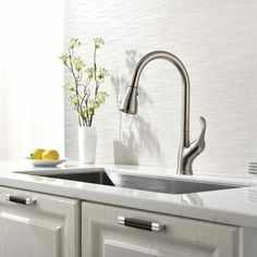 a kitchen sink sitting under a faucet next to a counter top with plates on it