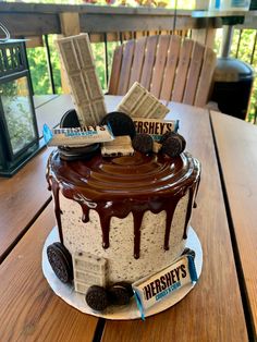 a chocolate cake with oreo cookies and hershey's on top sitting on a wooden table