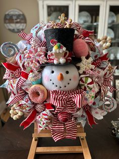 a christmas wreath with a snowman wearing a top hat and holding a donut