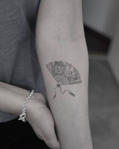 a woman's arm with a fan tattoo on it