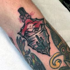 a man's arm with a tattoo on it that has a shield and cross