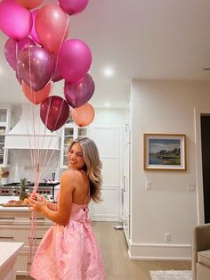 a woman in a pink dress holding balloons