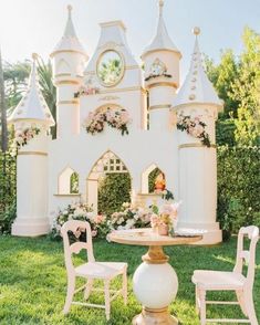 a table and chairs in front of a white castle with pink flowers on the walls