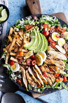 a salad with chicken, avocado, tomatoes and other toppings on it