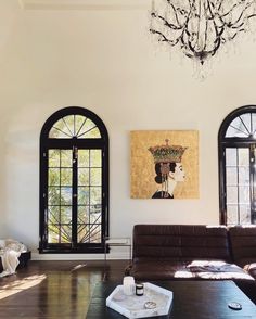 a living room filled with furniture and two large windows next to a chandelier