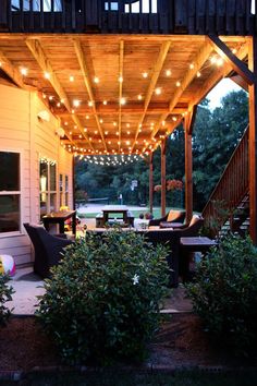 an outdoor covered patio with lights on the ceiling and seating area in the back yard