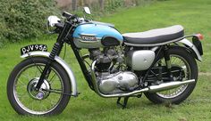 a blue and silver motorcycle parked on top of a lush green field