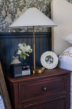 a nightstand with a lamp and pictures on it