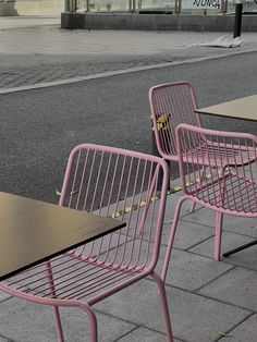 pink chairs and tables sitting on the sidewalk