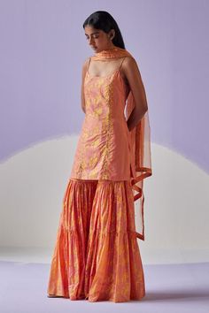 Coral orange noodle strap sleeves kurta in cotton silk base with all over bloomy print with dabka, beads embroidered highlights. Paired with matching tiered sharara and organza dupatta.
Components: 3
Pattern: Print, Embroidery
Type Of Work: Hand Block, Dabka and Beads
Neckline: Round
Sleeve Type: Noodle Strap
Fabric: Kurta and Sharara: Cotton Silk, Dupatta: Organza
Color: Orange
Other Details: 
Length(in inches):
Kurta: 32
Sharara: 44
Dupatta: 38
Occasion: Puja - Aza Fashions Orange Chikankari Embroidery Palazzo Set For Designer Wear, Orange Chikankari Embroidery Palazzo Set, Summer Cotton Silk Salwar Kameez With Gota Work, Orange Chanderi Sharara, Orange Cotton Sets With Printed Motifs, Fitted Orange Cotton Traditional Wear, Orange Cotton Traditional Wear With Zari Work, Festive Orange Salwar Kameez With Printed Motifs, Orange Chanderi Palazzo Set