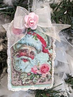 an ornament hanging from a christmas tree with a pink rose on it's head