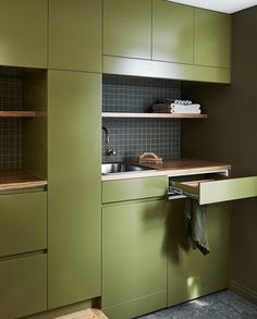 a kitchen with green cupboards and a sink in the corner, next to a counter