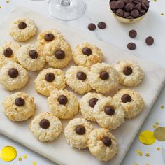 cookies and chocolate chips are arranged on a white cutting board next to glasses of wine