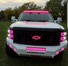 the front end of a white truck with pink lights on it's grilles