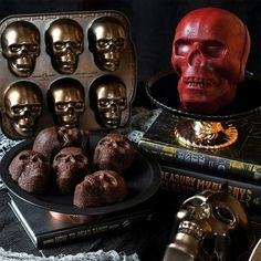 there are many skull heads on the table next to some chocolates and other items