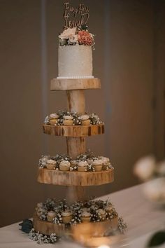 a three tiered cake sitting on top of a table next to cupcakes