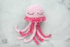 a pink and white crocheted octopus with eyes closed