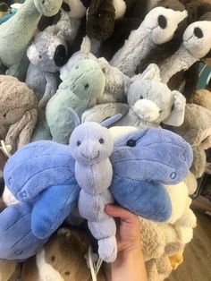 a person holding a bunch of stuffed animals in front of a pile of other stuffed animals