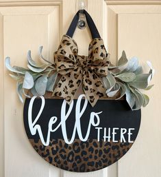 a door hanger that says hello there with a leopard print bow hanging on it