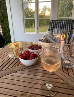 a glass of wine and bowl of strawberries on a table