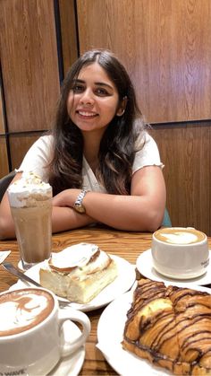 a woman sitting at a table with desserts and coffee