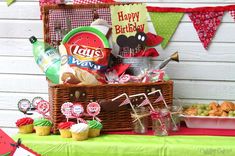 a birthday party with cupcakes, candy and treats in a basket on the table