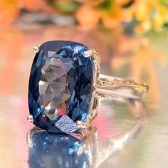 a ring with an oval cut blue sapphire surrounded by yellow and white diamonds on a shiny surface