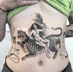 a woman with tattoos on her stomach holding a tiger in front of her belly and wearing a green shirt