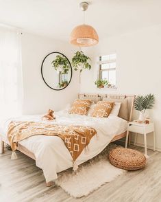 a bedroom with white walls and wood flooring is pictured in this image, there are plants on the bed