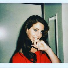 a woman in a red shirt posing for the camera with her hand on her mouth